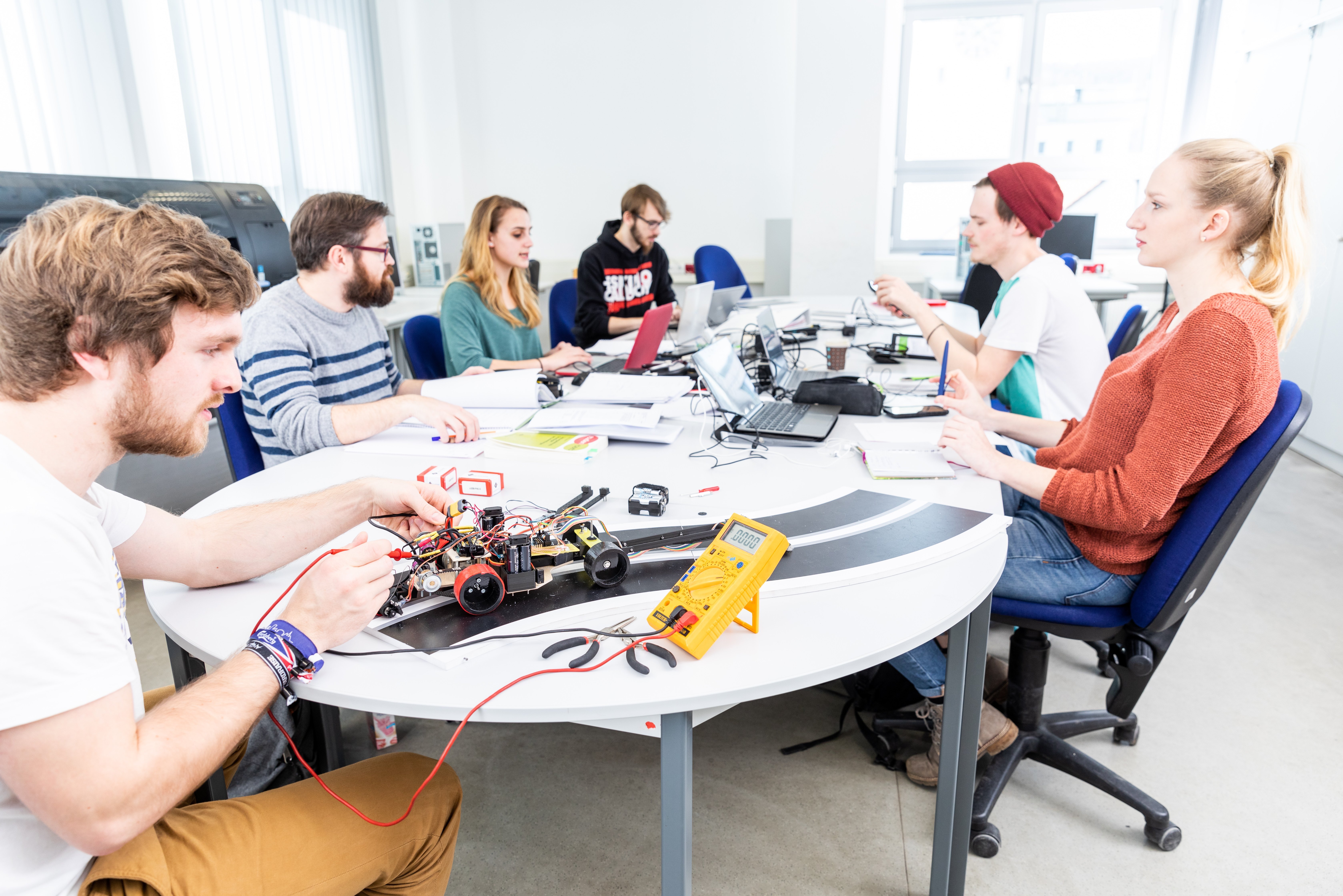 Studierende arbeiten an einem Elektronikprojekt mit Miniaturfahrzeug – Lehrsituation im Studienschwerpunkt Technik an der Ernst-Abbe-Hochschule Jena