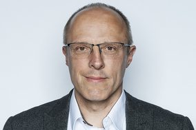 Mann mittleren Alters mit Brille Blickt freundlich in die Kamera