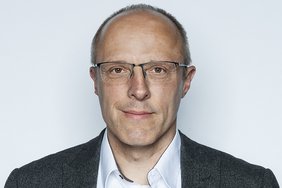 Mann mittleren Alters mit Brille Blickt freundlich in die Kamera