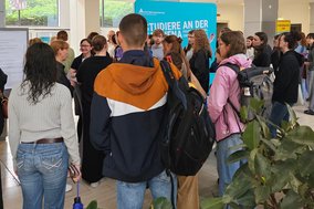 Eine große Gruppe Menschen drängt sich in einem Raum um verschiedene Informationsstände