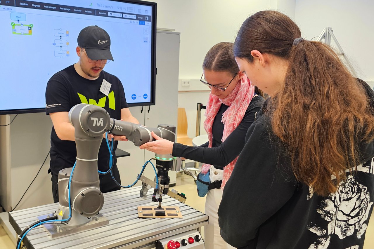 Zwei Schülerinnen arbeiten mit einem kollaborierenden Roboter