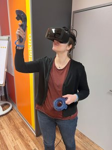 Foto einer VR-Studienteilnehmerin mit Virtual-Reality-Brille und Controllern