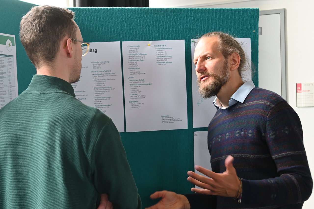 Austausch am Thementisch bei der FDM-Veranstaltung "Treasure your data" Zwei Männer beim intensiven Austausch vor einer Posterwand, am Thementisch zu Software für den Datenalltag