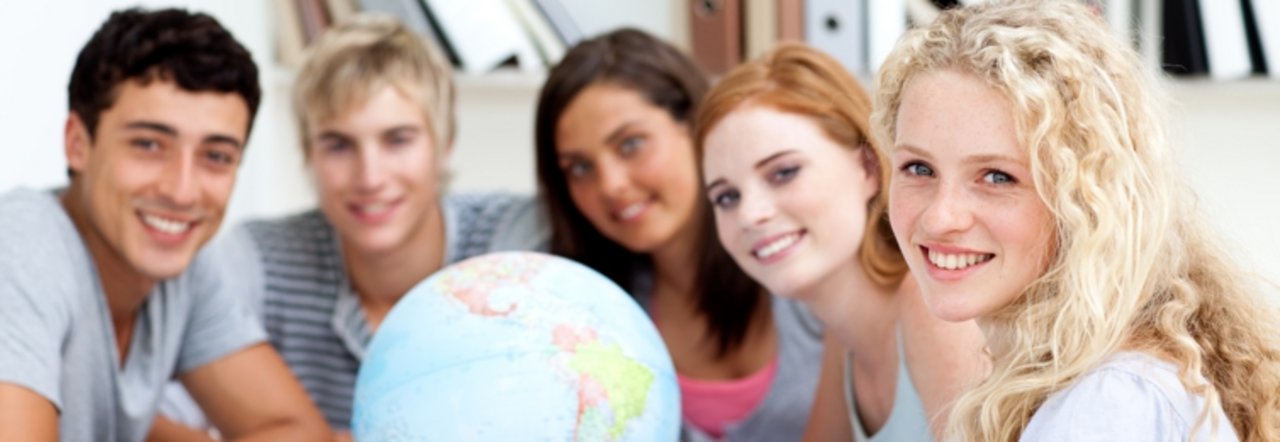 Foto internationale Studierende sitzen um einen Globus