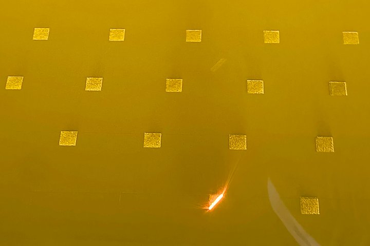 Auf einer Metallplatte hat ein Laser bereits mehrere würfelförmige Proben geschmolzen und schmilzt gerade eine weitere.
