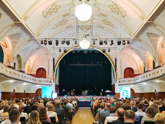 Blick in einen festlichen Saal mit vielem Publikum.