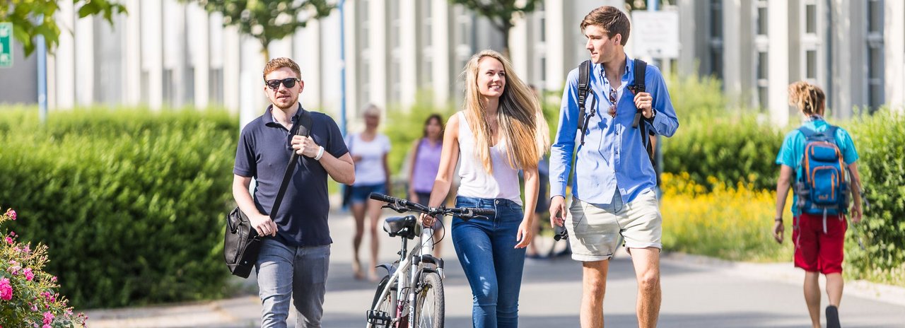 Zu sehen sind Studierende, welche über den Campus laufen