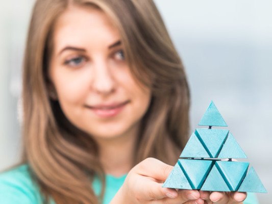 Eine Frau hält ein türkisfarbenes Modell des Hochschullogos in der Hand.