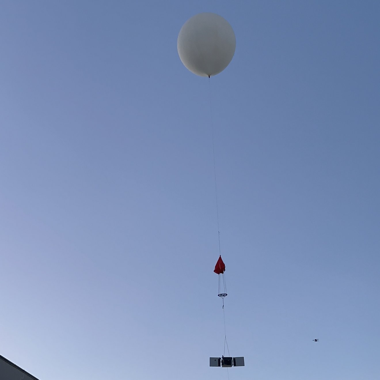 Ein großer Stratosphärenballon steigt mit einer kleinen technischen Nutzlast über dem Campus in die Höhe.