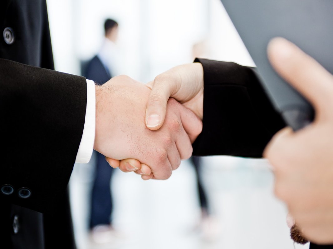 Zwei Personen geben sich die Hand. Sie tragen Businesskleidung.