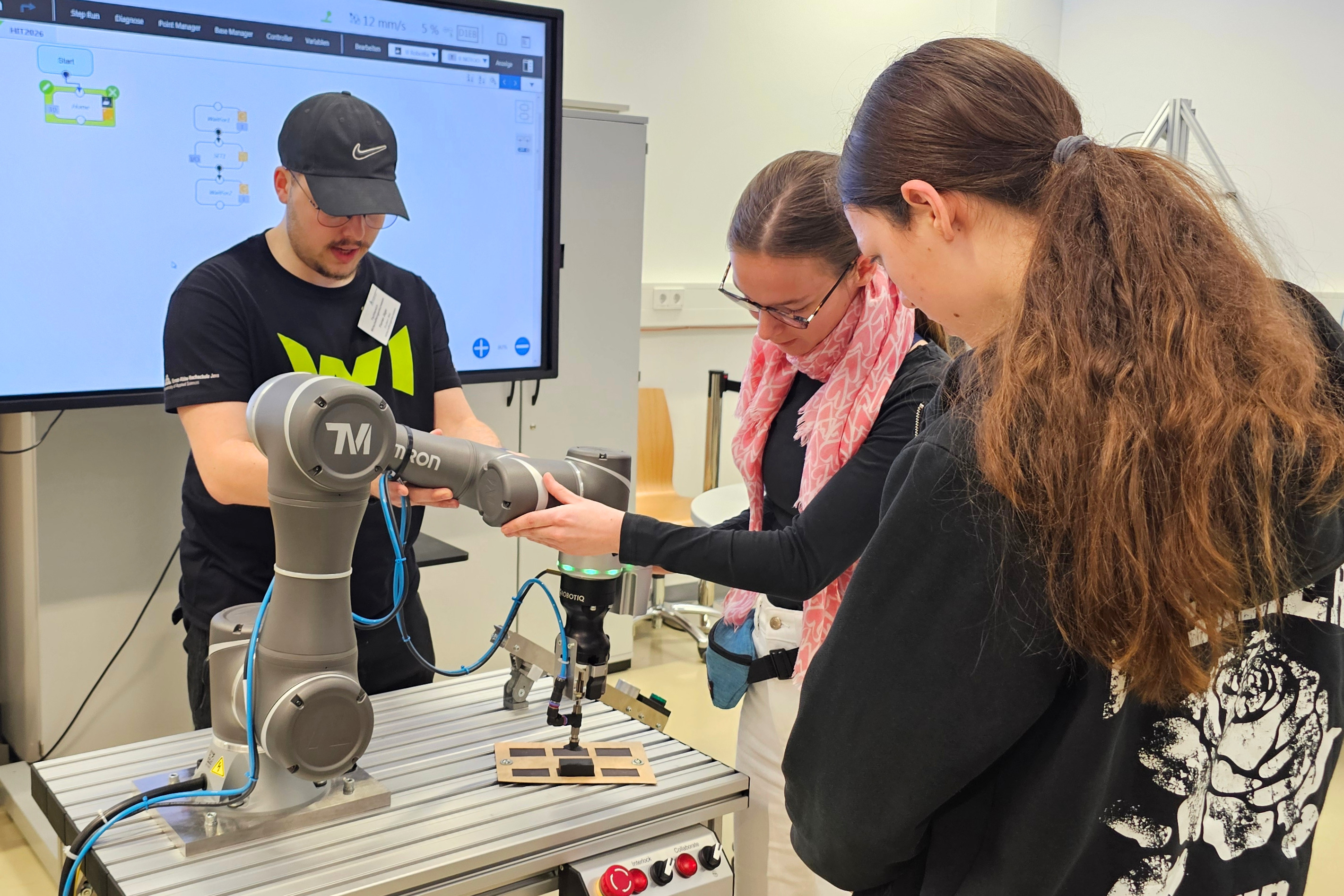 Zwei Schülerinnen arbeiten mit einem kollaborierenden Roboter
