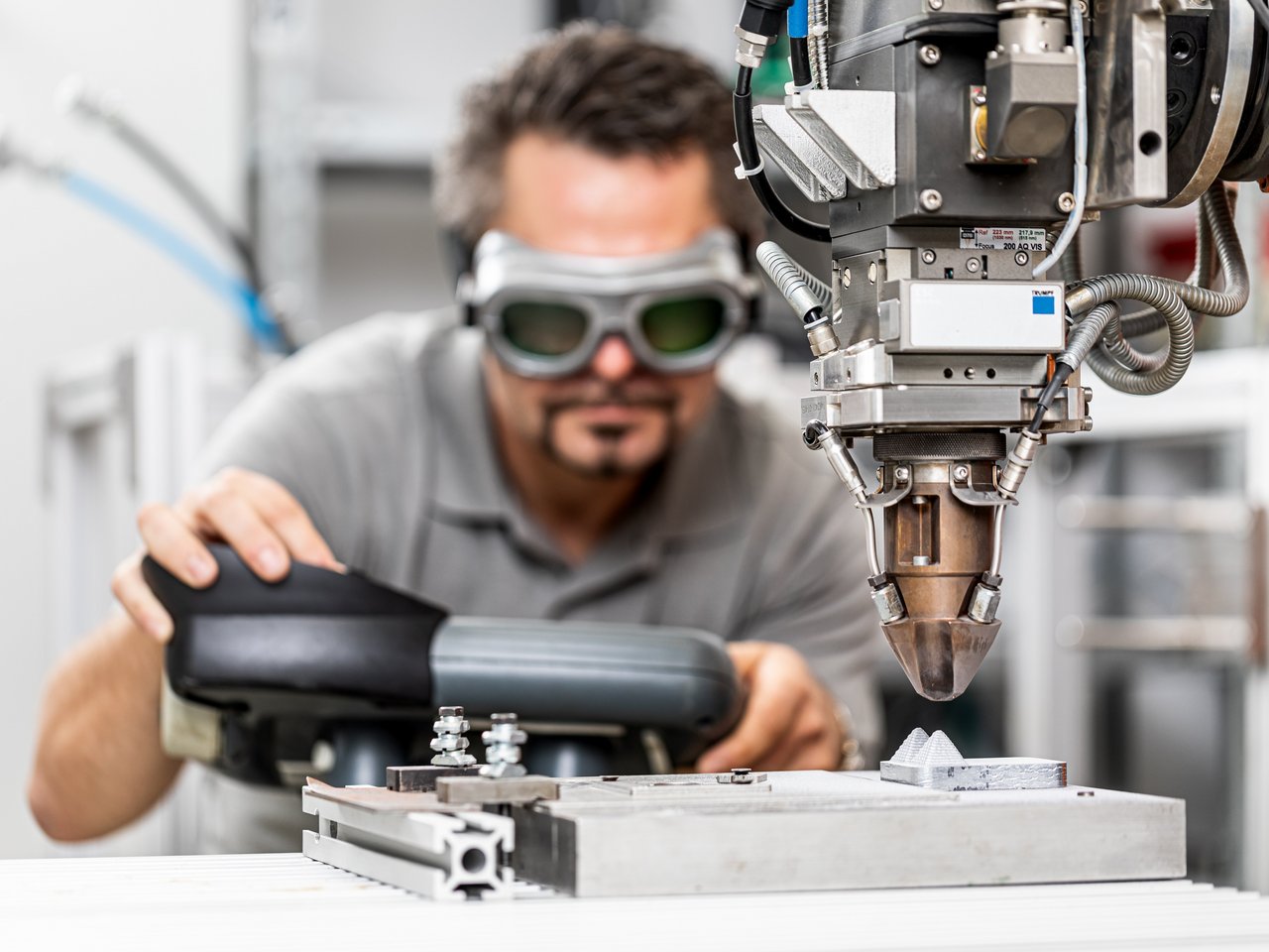 Wissenschaftler mit Schutzbrille arbeitet mit Roboterarm